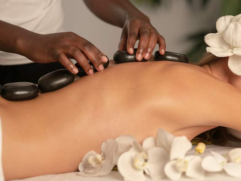 Cuidado corporal manual com pedras aquecidas em ambiente de spa